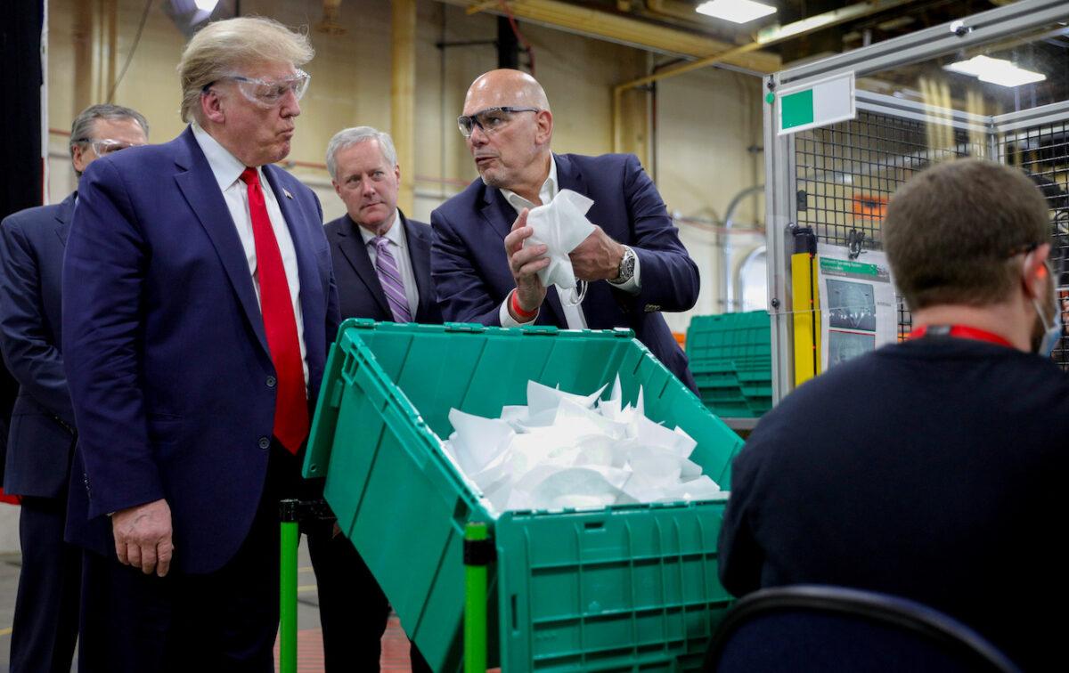 President Donald Trump is shown a protective face mask by Honeywell's Vice President of Integrated Supply Chain Tony Stallings along with White House Chief of Staff Mark Meadows while touring Honeywell's manufacturing facility for the CCP virus outbreak in Phoenix, Ariz., on May 5, 2020. (Tom Brenner/Reuters)