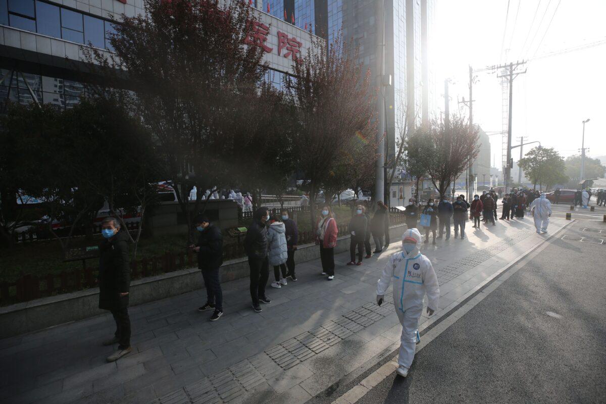 Patients who recovered from the COVID-19 CCP virus line up to be tested again as a medical worker looks on, outside a hospital in Wuhan, in China's central Hubei province, China, on March 14, 2020. (STR/AFP via Getty Images)