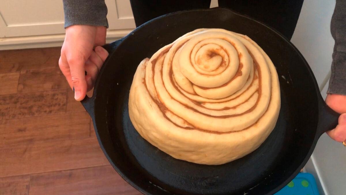 Whitney Rutz displays a large cinnamon roll before putting it in the oven. (Whitney Rutz via AP)