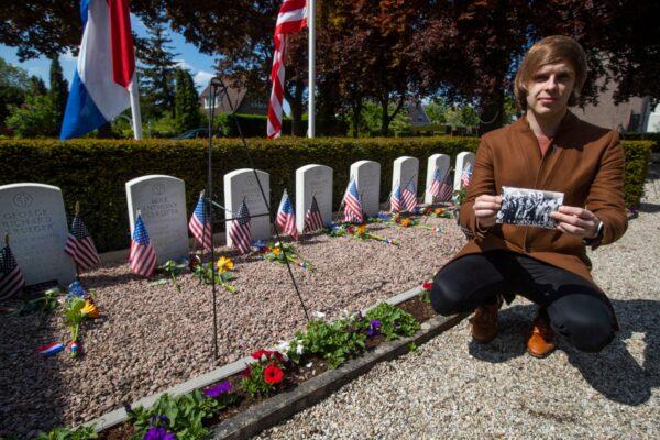 Historian Sebastiaan Vonk poses with a picture of the crew at the graves of eight members of the crew of an American B17 bomber shot down over the Netherlands on July 30, 1943, in the tiny rural village of Opijnen, Netherlands, on May 4, 2020. (Peter Dejong/AP Photo)
