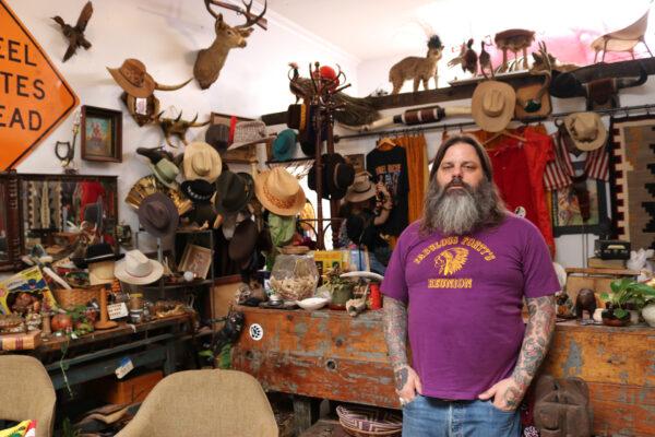 Matt De Vaul stands with some of the collectibles found in MMD Antiques in Orange, Calif., on May 7, 2020. (Jamie Joseph/The Epoch Times)
