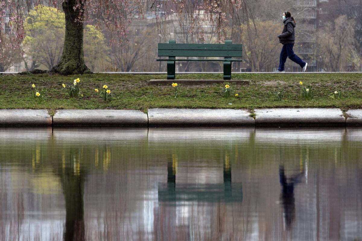 A woman wearing a protective mask walks along the Esplanade, , in Boston, on May 1, 2020. (Michael Dwyer/AP Photo)