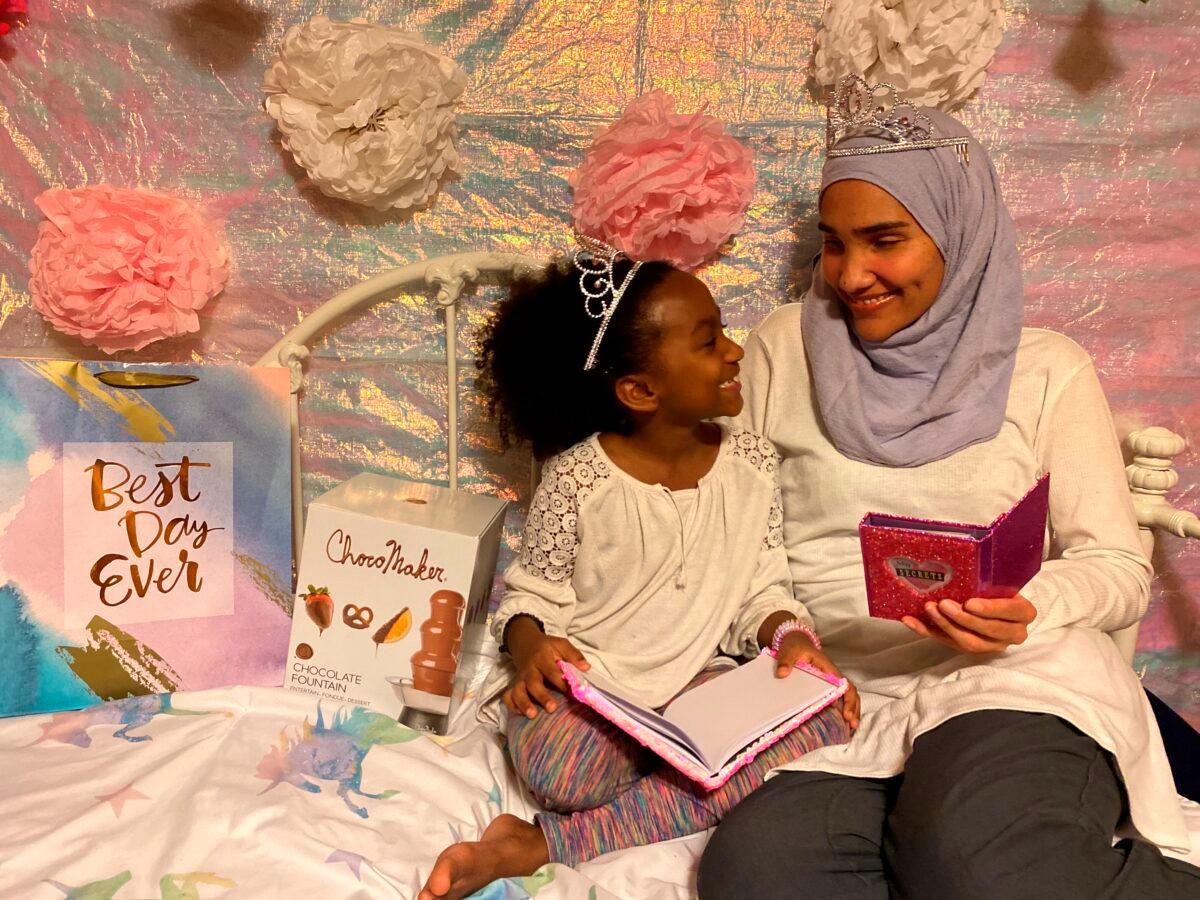 Melissa Mueller-Douglas (R) and her 7-year-old daughter, Nurah, at their home in Rochester, N.Y., with some of the items they plan to use for a Mother’s Day sleepover. (Yakub Shabazz via AP)