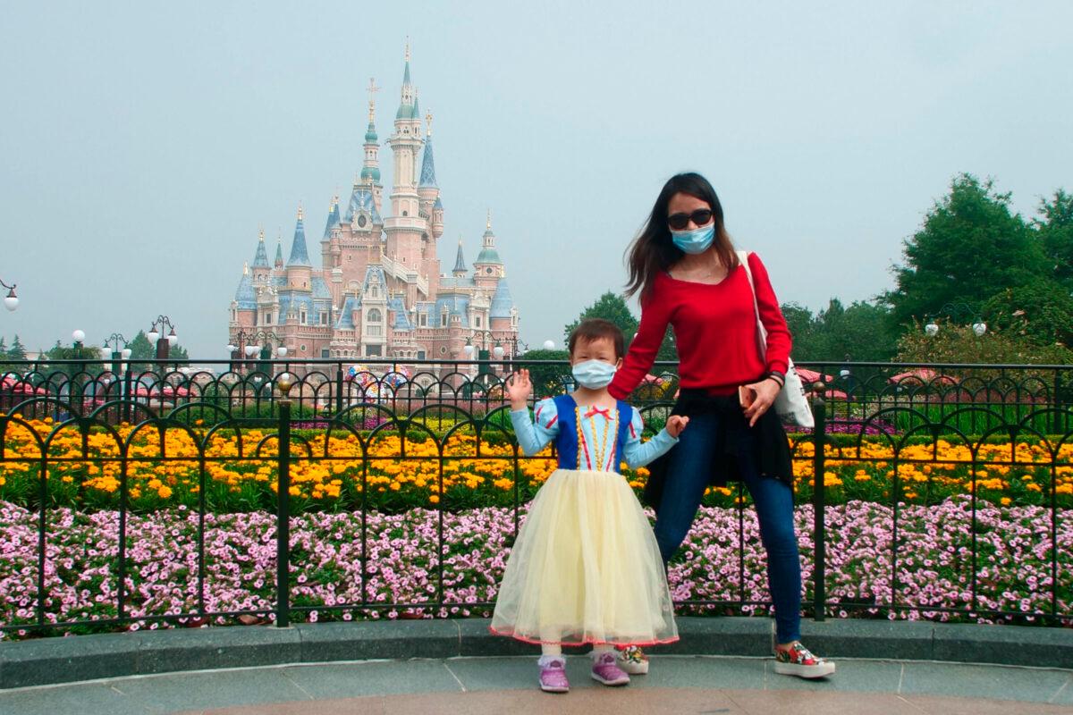A young visitor, wearing face masks, waves at the Disneyland theme park in Shanghai as it reopened after the CCP virus closure, on May 11, 2020. (Sam McNeil/AP Photo)
