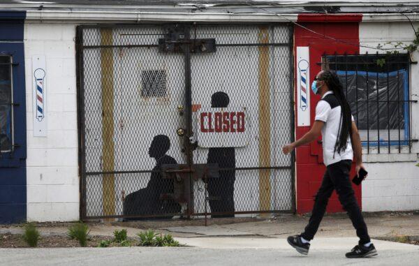 A pedestrian walks past a closed barber shop in Ward 7 in Washington, on May 8, 2020. (Leah Millis/Reuters)