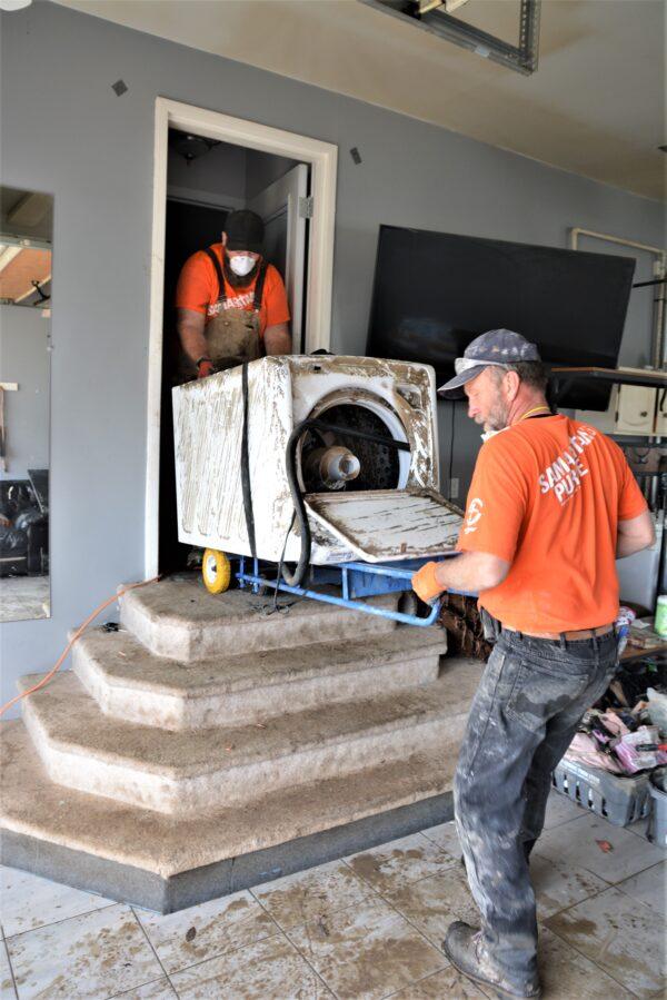 Volunteers with Samaritan’s Purse move a washing machine out of a flood-damaged home in Fort McMurray. (Courtesy of Samaritan’s Purse)