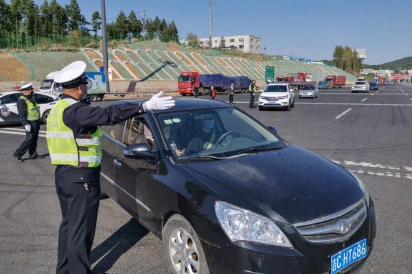 A police officer guides a car driver to register information at an exit of a highway in Jilin, China, on May 13, 2020. (STR/AFP via Getty Images)