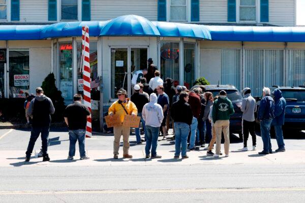 People wait in line to have their hair cut in front of the shop of barber Karl Manke, who faces two misdemeanor charges for reopening his business despite state shutdown orders, in Owosso, Mich., on May 12, 2020. (Jeff Kowalsky/AFP via Getty Images)