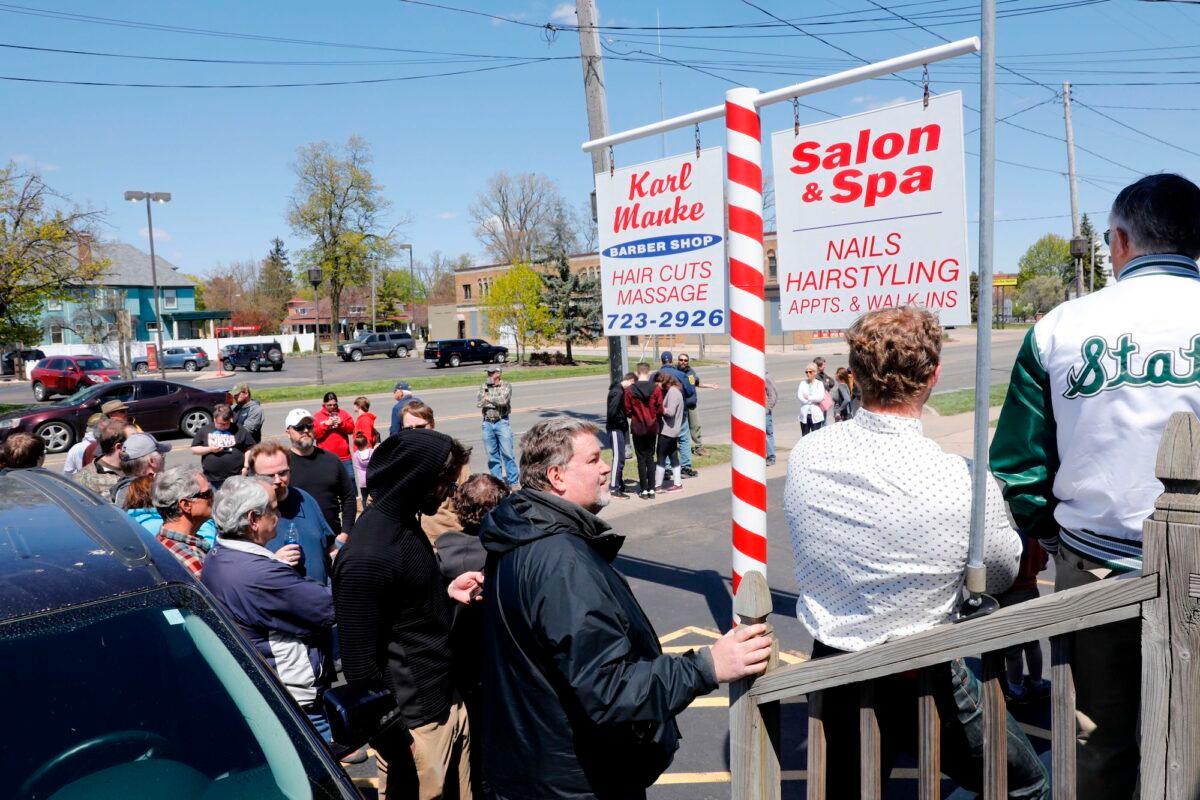 People wait in line to have their hair cut in front of the shop of Barber Karl Manke, in Owosso, Mich., on May 12, 2020. (Jeff Kowalsky/AFP/Getty Images)