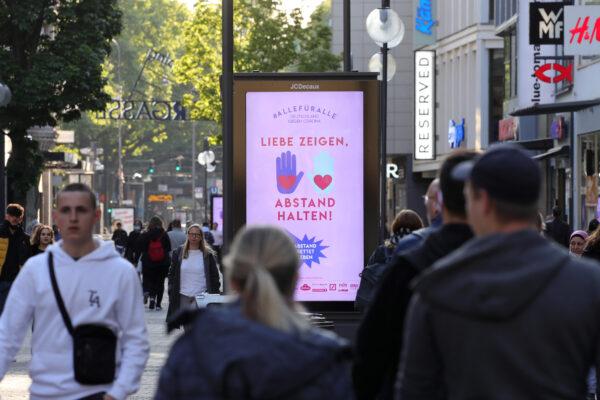 People walking past a sign on a shopping street that says 'Show love - Keep distance' in Cologne, Germany, on May 12, 2020. (Andreas Rentz/Getty Images)