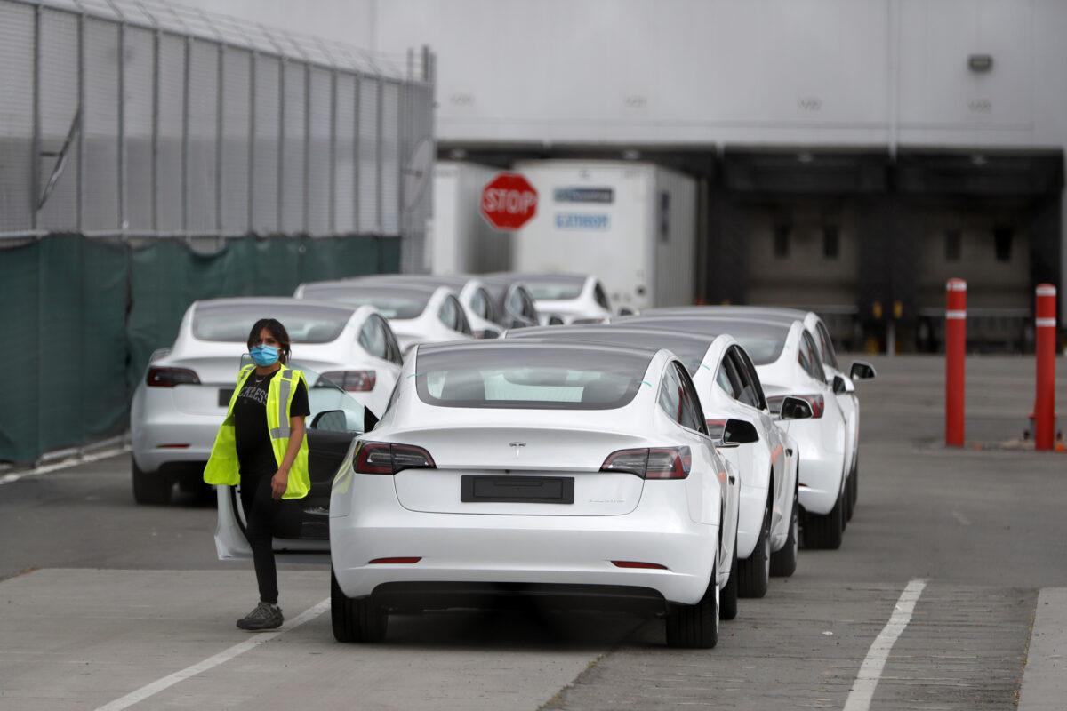 A worker exits a Tesla Model 3 electric vehicle at Tesla's primary vehicle factory after CEO Elon Musk announced he was defying local officials' CCP virus restrictions by reopening the plant in Fremont, Calif. on. May 11, 2020. (Stephen Lam/Reuters)