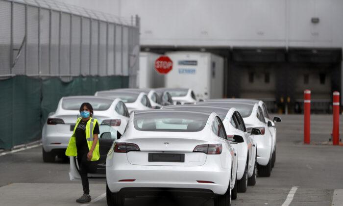 A worker exits a Tesla Model 3 electric vehicle at Tesla's primary vehicle factory in Fremont, Calif., on. May 11, 2020. (Stephen Lam/Reuters)