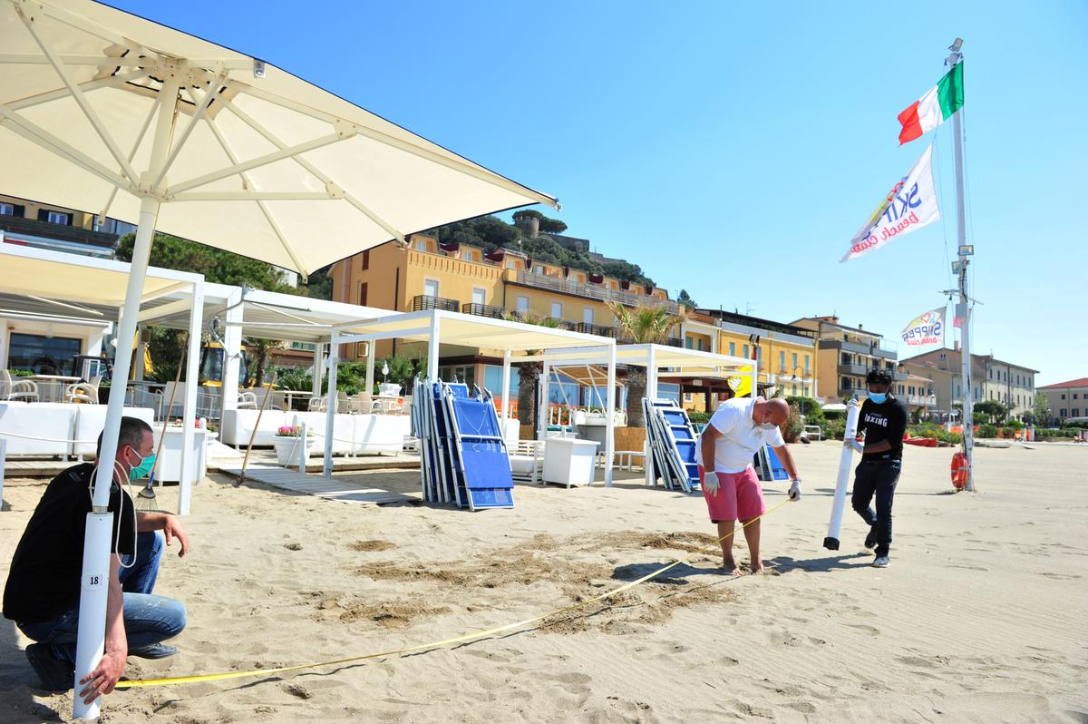 Workers at a beach club wearing protective masks and gloves make preparations to open in Castiglione della Pescaia, Italy, on April 24, 2020. (REUTERS/Jennifer Lorenzini/File Photo)