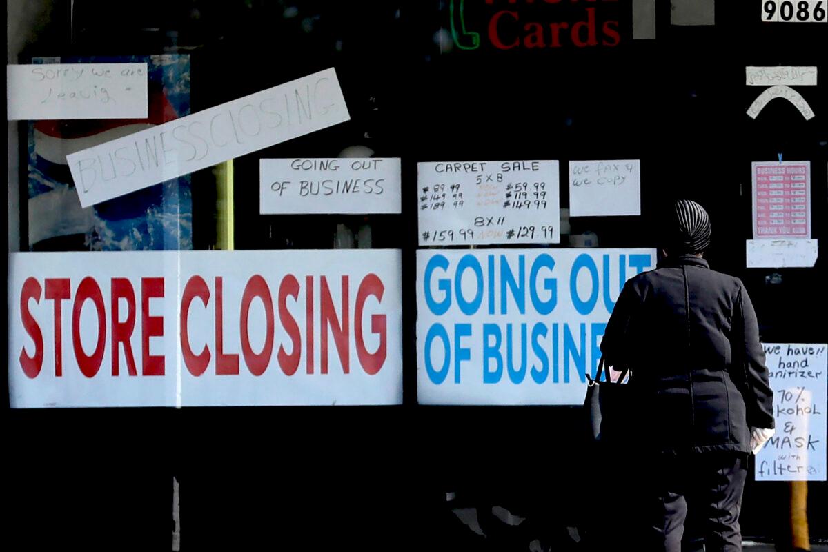 A woman looks at signs at a store closed due to COVID-19 in Niles, Ill., on May 13, 2020. (Nam Y. Huh/AP Photo)