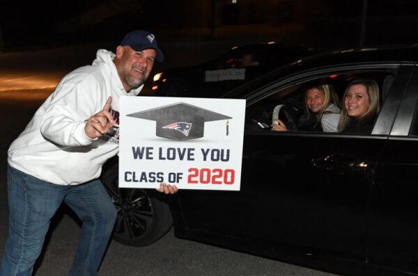 Principal Derek Bellow holds a sign as students drive by during a celebration to recognize seniors in the class of 2020 at Liberty High School in Henderson, Nevada, on April 17, 2020. Students remained in vehicles to maintain social distancing as they drove through the school parking lot and their teachers and staff greeted them and cheered. (Photo by Ethan Miller/Getty Images)