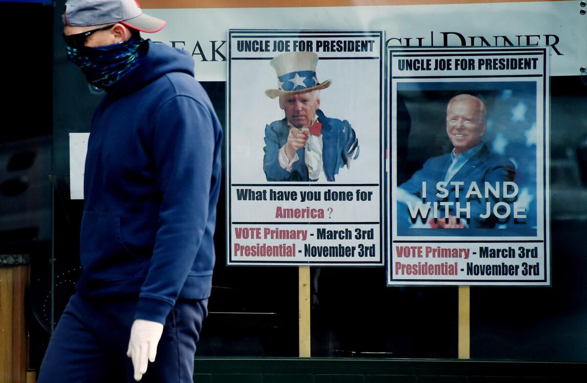 A man wearing a face mask walks past signs for Joe Biden's 2020 presidential campaign amid the CCP virus outbreak in Alexandria, Virginia on May 11, 2020. (Olivier Douliery/AFP via Getty Images)