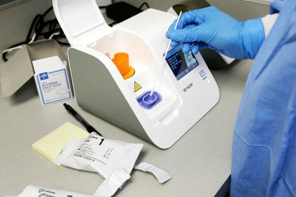 A lab technician dips a sample into the Abbott Laboratories ID Now testing machine at the Detroit Health Center in Detroit on April 10, 2020. (Carlos Osorio/AP Photo)