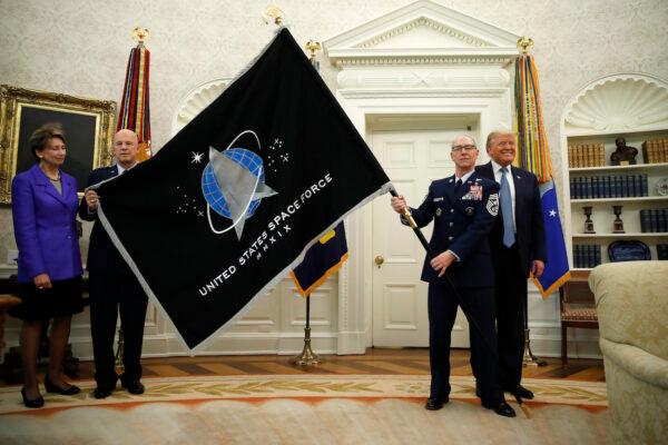 President Donald Trump stands as Chief of Space Operations as U.S. Space Force Gen. John Raymond, second from left, and Chief Master Sgt. Roger Towberman, second from right, hold the United States Space Force flag as it is presented in the Oval Office of the White House on May 15, 2020. Secretary of the Air Force Barbara Barrett stands to the far left. (AP Photo/Alex Brandon)