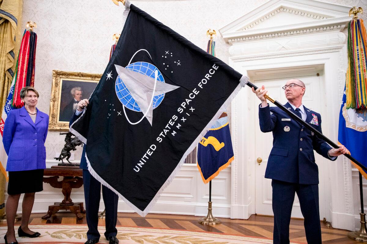 (R) Gen. Jay Raymond, chief of Space Operations, and (L) Chief Master Sgt. Roger Towberman, with Secretary of the Air Force Barbara Barrett, present President Donald Trump with the official flag of the United States Space Force in the Oval Office of the White House in Washington, on May 15, 2020. (Samuel Corum-Pool/Getty Images)