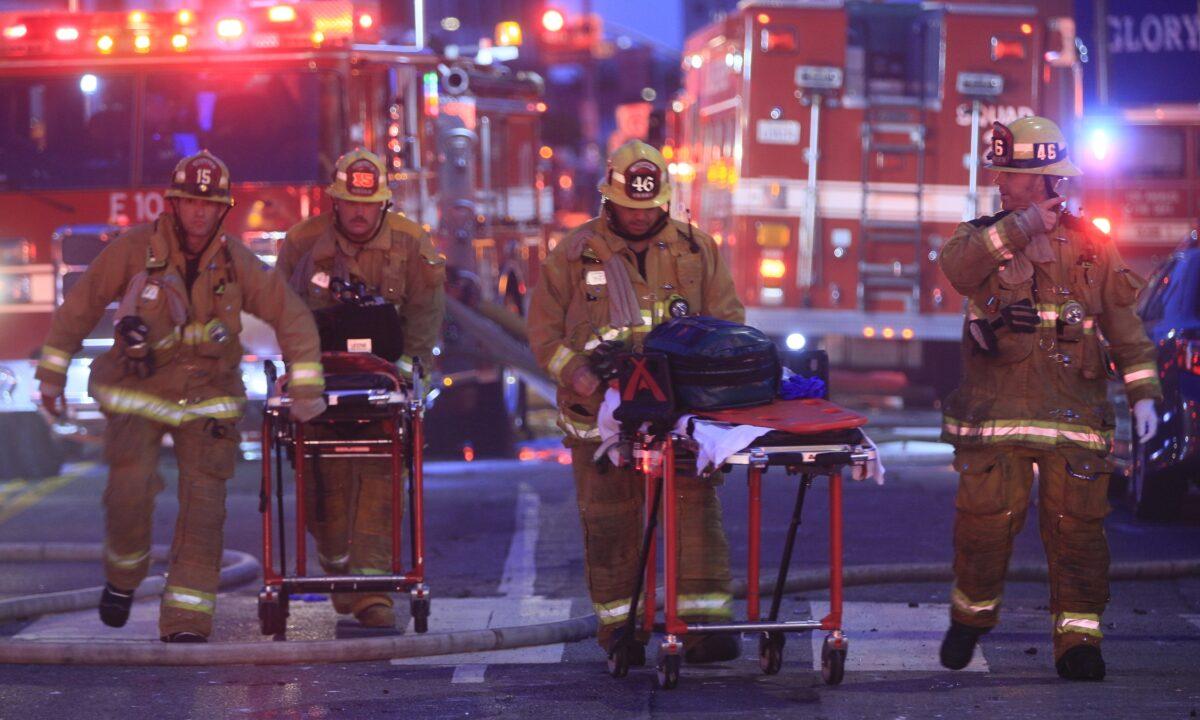 Los Angeles Fire Department firefighters push ambulance cots at the scene of a structure fire that injured multiple firefighters, according to a fire department spokesman, in Los Angeles, on May 16, 2020. (Damian Dovarganes/AP Photo)