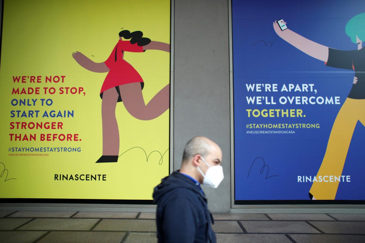 A man wearing a face mask walks past billboards of La Rinascente department store, which is due to reopen with social distancing measures applied, after it was closed due to the spread of the CCP virus in Milan, Italy, on May 16, 2020. (Alessandro Garofalo/Reuters)