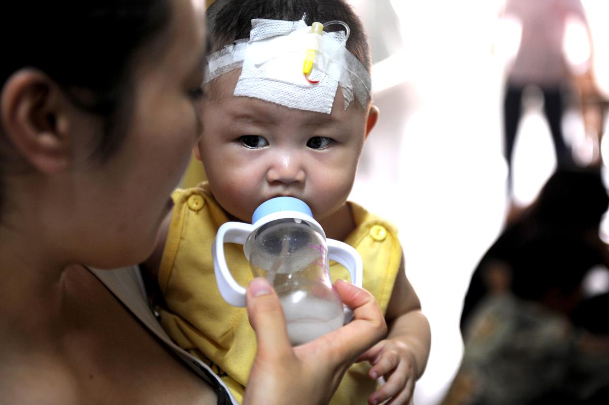 A woman feeds a baby who suffers from kidney stones after drinking tainted milk powder at the Chengdu Children's Hospital in Chengdu, China, on Sept. 22, 2008. (China Photos/Getty Images)