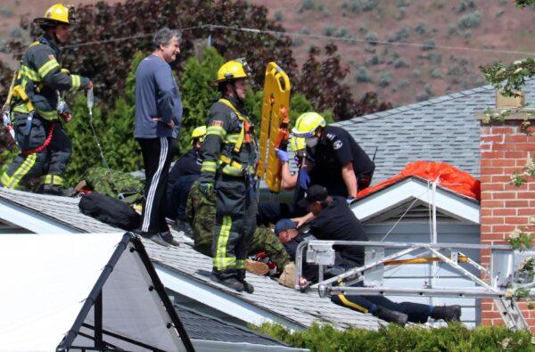 First responders attend to a person on a rooftop at the scene of a crash involving a Canadian Forces Snowbirds airplane in Kamloops, British Columbia, Canada, on May 17, 2020. (Brendan Kergin/Castanet Kamloops/The Canadian Press via AP)
