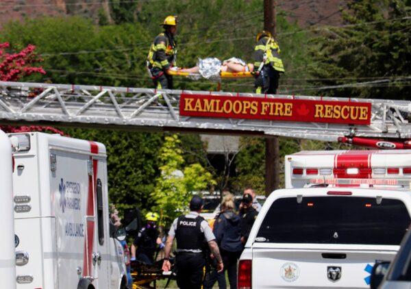 First responders carry an injured person on a stretcher across a fire truck ladder from a rooftop at the scene of a crash involving a Canadian Forces Snowbirds airplane in Kamloops, British Columbia, Canada, on May 17, 2020. (Brendan Kergin/Castanet Kamloops/The Canadian Press via AP)