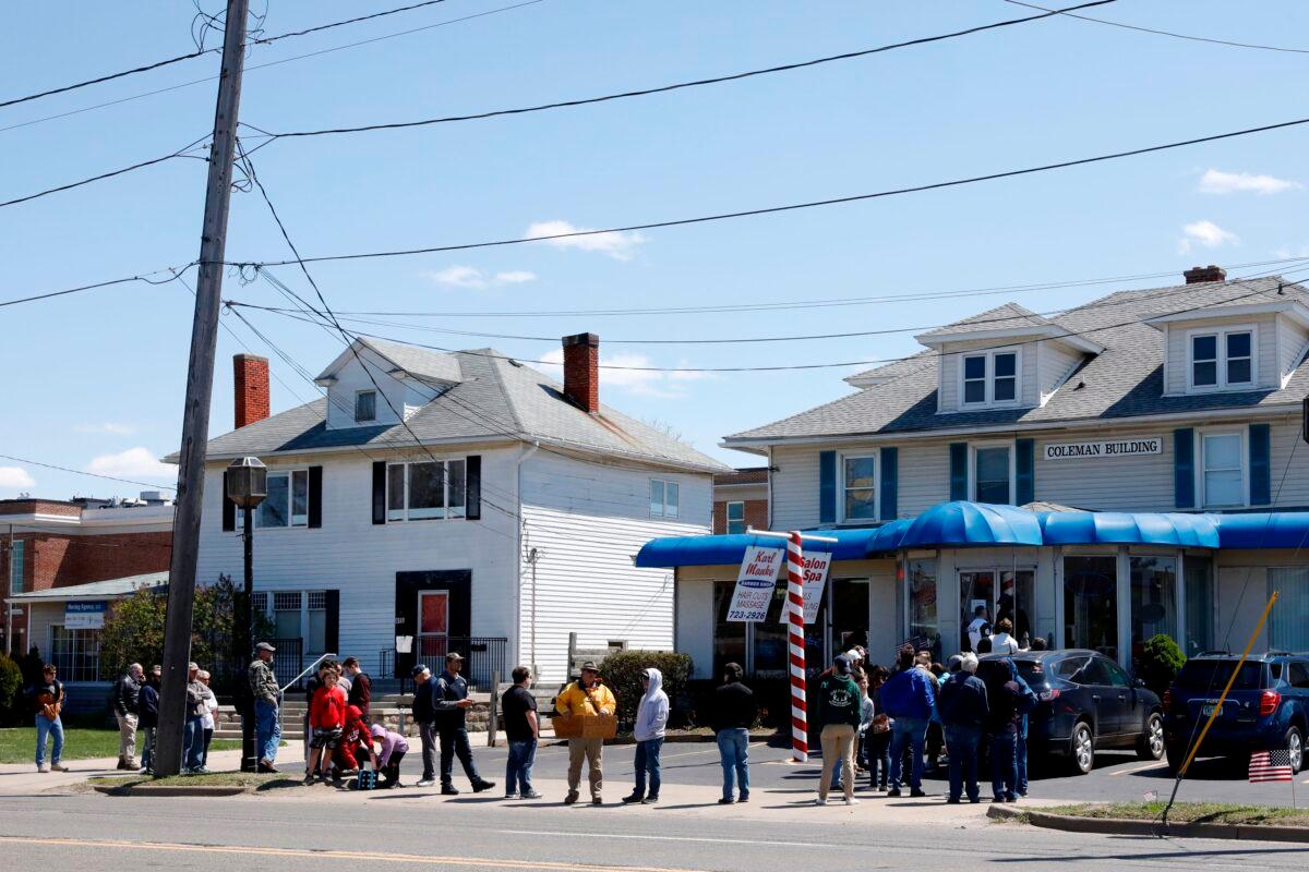 People wait in line to have their hair cut in front of the shop of Barber Karl Manke, who faces two misdemeanor charges for reopening his business despite state shutdown orders, in Owosso, Mich. on May 12, 2020. (Jeff Kowalsky/AFP via Getty Images)