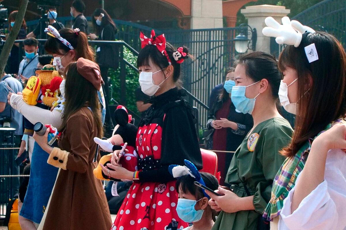 Visitors, wearing face masks, wait to enter the Disneyland theme park in Shanghai as it reopened on May 11, 2020. (Sam McNeil/AP Photo)