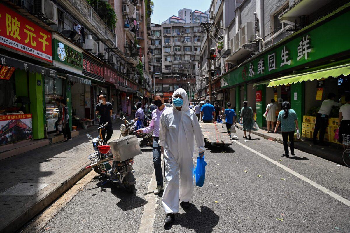 A man wearing protective gear walks past shops in Wuhan, Hubei Province, China, on May 18, 2020. (Hector Retamal/AFP via Getty Images)