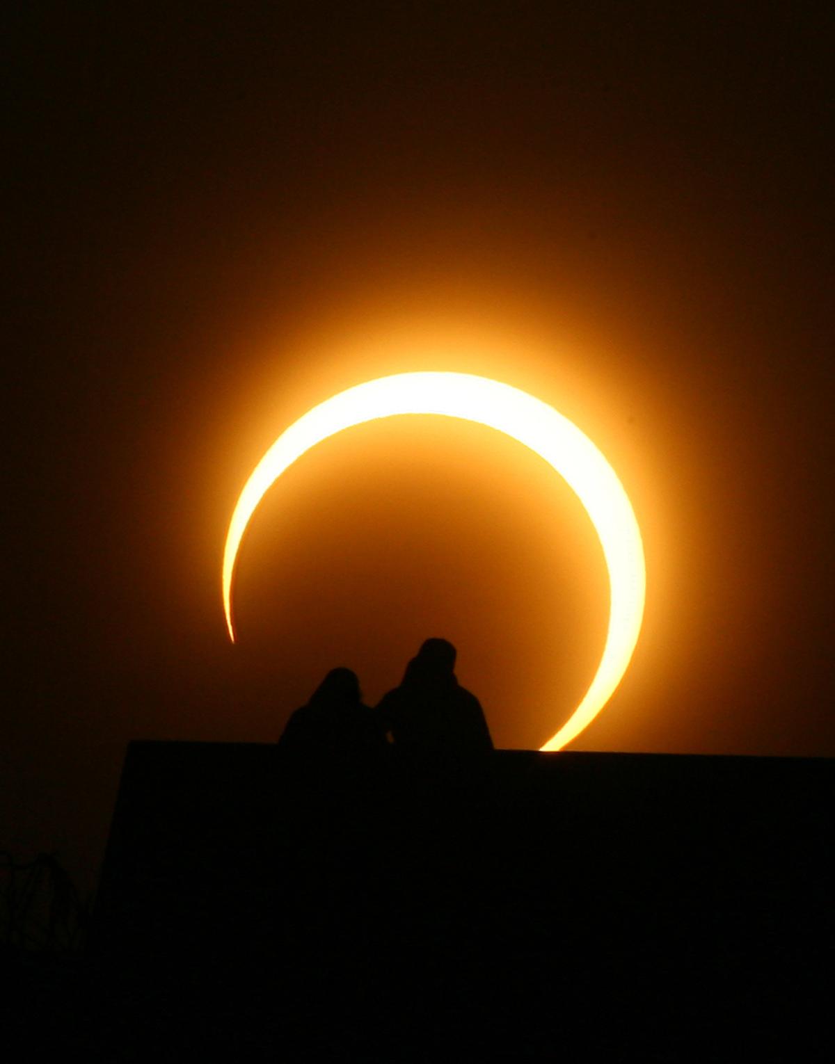 A couple watches the solar eclipse over Zhengzhou in central China's Henan province on Jan. 15, 2010. (STR/AFP via Getty Images)