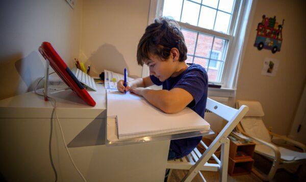 Colin, 10, whose school was closed following the CCP virus outbreak, does schoolwork at home in Washington on March 20, 2020. (Eric Baradat/AFP via Getty Images)