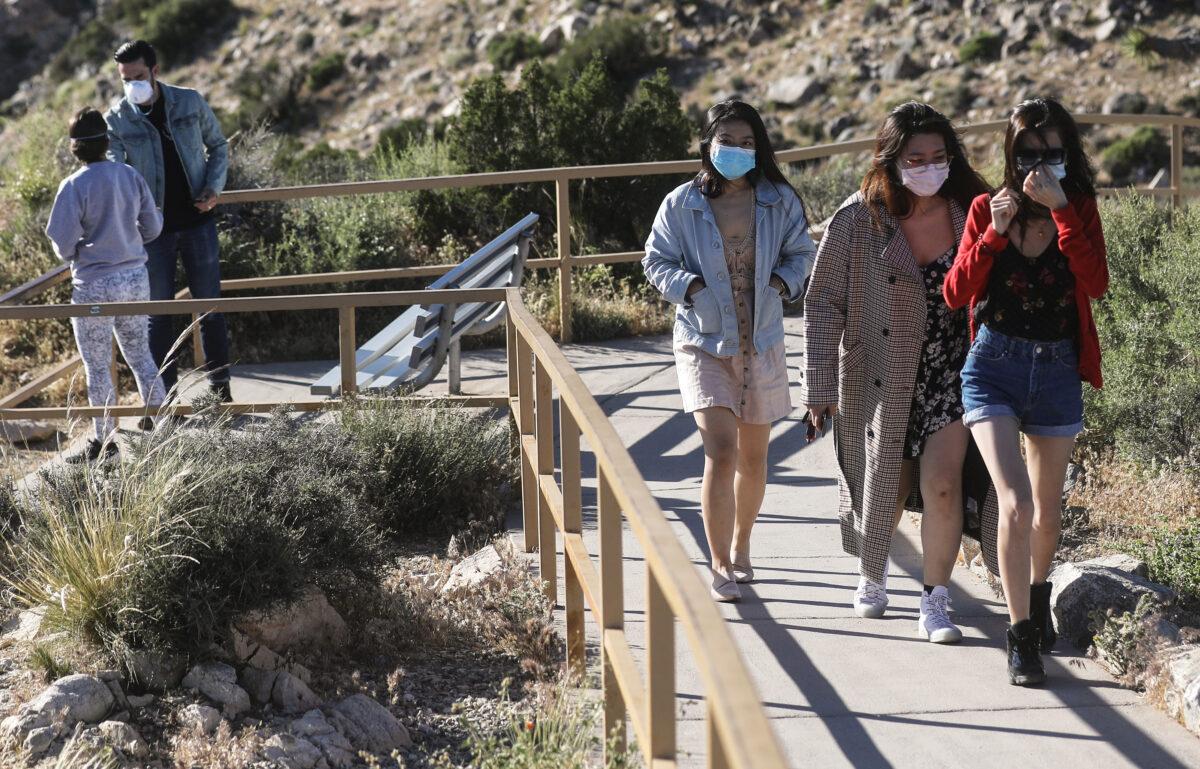 Visitors wear face masks on a walking path in Joshua Tree National Park one day after the park reopened after being closed for two months due to the COVID-19 pandemic in Joshua Tree National Park, Calif. on May 18, 2020. (Mario Tama/Getty Images)