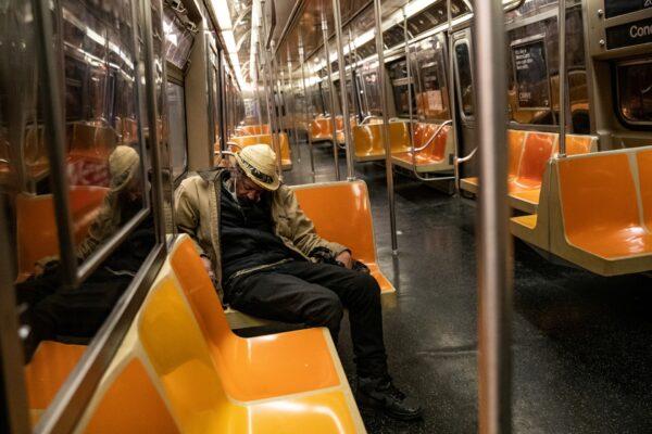 A passenger sleeps inside an MTA subway car during the outbreak of the CCP virus in New York City, N.Y., on May 6, 2020. (Jeenah Moon/File Photo/Reuters)