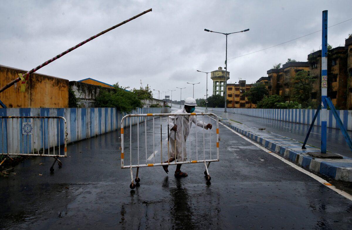 A police officer moves a barricade to block a road leading to a flyover before Cyclone Amphan makes its landfall, in Kolkata, India, on May 20, 2020. (Rupak De Chowdhuri/Reuters)