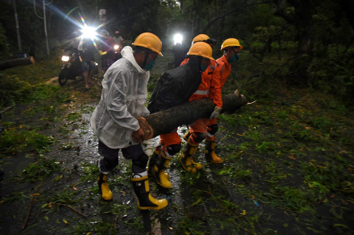 Members of the National Disaster Rescue Force remove a branch of an uprooted tree after Cyclone Amphan made its landfall, in Digha, near the border between the eastern states of West Bengal and Odisha, India, on May 20, 2020. (Stringer/Reuters)