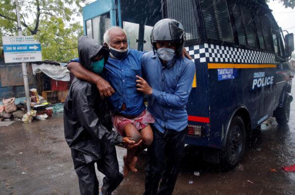 Police officers carry a disabled man to a safer place following his evacuation from a slum area before Cyclone Amphan makes its landfall, in Kolkata, India, on May 20, 2020. (Rupak De Chowdhuri/Reuters)