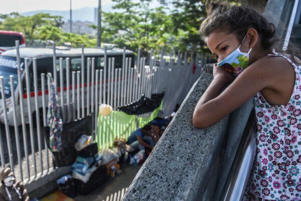 A Venezuelan migrant girl wanting to return to her country due to the CCP virus pandemic, waits outside the bus terminal, for a chance to get on a bus to the border, Medellin, Colombia, on May 14, 2020. (Joaquin Sarmiento /AFP/Getty Images)