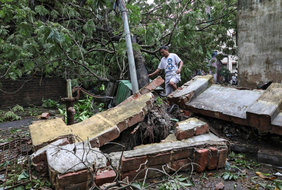 A man walks over a collapsed wall after Cyclone Amphan made its landfall, in Kolkata, India, on May 21, 2020. (Rupak De Chowdhuri/Reuters)