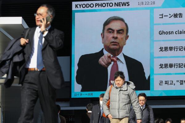 Pedestrians walk past a big screen showing images of former Nissan Motor Co. Chairman Carlos Ghosn in a news program on January 09, 2020 in Tokyo, Japan. Ghosn was awaiting trial in Japan on charges of financial crimes when he fled house arrest in Tokyo, arriving in Beirut on Dec. 30, 2019. (Takashi Aoyama/Getty Images)
