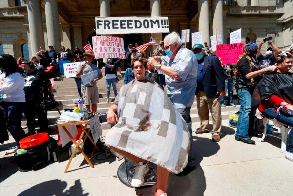 The media record barber Karl Manke, of Owosso, giving a free haircut to Parker Shonts on the steps of the State Capitol during a rally in Lansing, Mich., on May 20, 2020. (Paul Sancya/AP Photo)