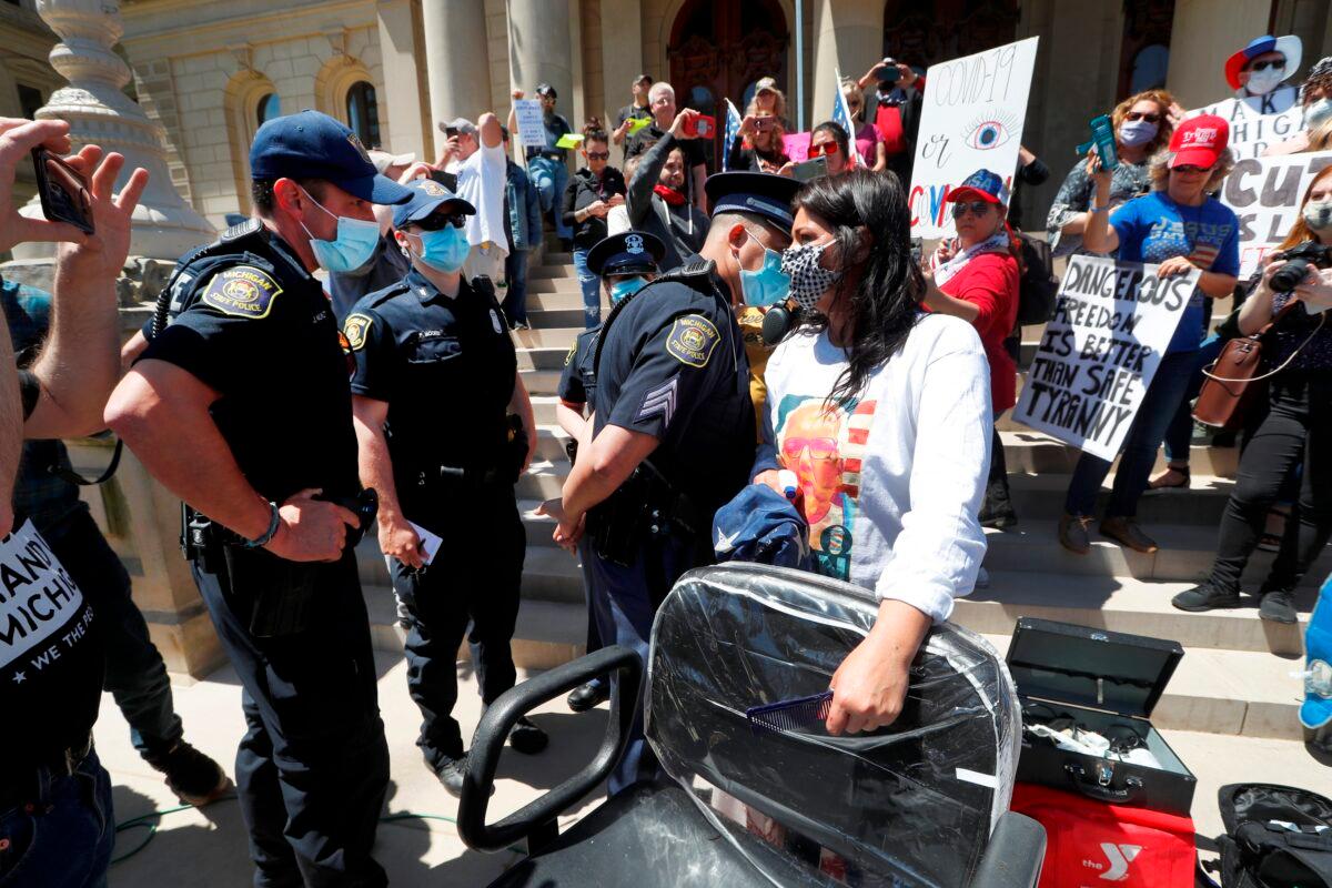 A Michigan State Police trooper talks with hair stylist Jody Hebberd while giving free haircuts at the State Capitol during a rally in Lansing, Mich., on May 20, 2020. (Paul Sancya/AP Photo)