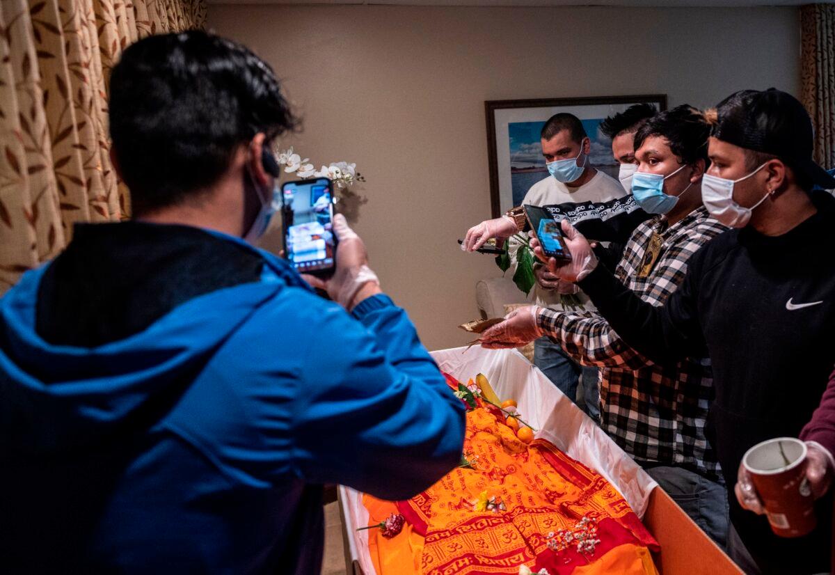 A family live streams a funeral in Millersville, Md. on May 20, 2020. The deceased died in a drowning but due to restrictions in place amid the COVID-19 pandemic, only eight close family members and friends were allowed to attend the ceremony inside, while more then 30 waited outside. Relatives in Nepal watched via livestream. (Andrew Caballero-Reynolds/AFP via Getty Images)