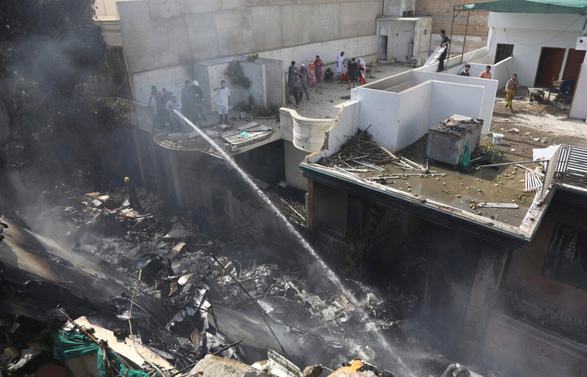 Fire brigade staff try to put out fire caused by plane crash in Karachi, Pakistan, on May 22, 2020. (Fareed Khan/AP Photo)