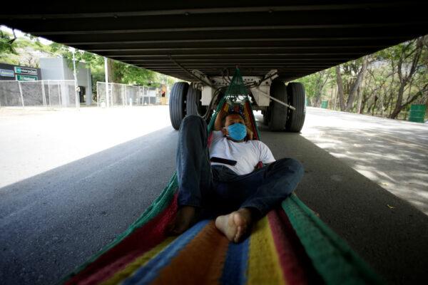 A trucker sleeps in a hammock tied under a truck trailer at the border between Costa Rica and Nicaragua, after Nicaragua's government closed the border for freight traffic, during the outbreak of the CCP virus (COVID-19), in Penas Blancas, Costa Rica on May 21, 2020. (Juan Carlos Ulate/Reuters)