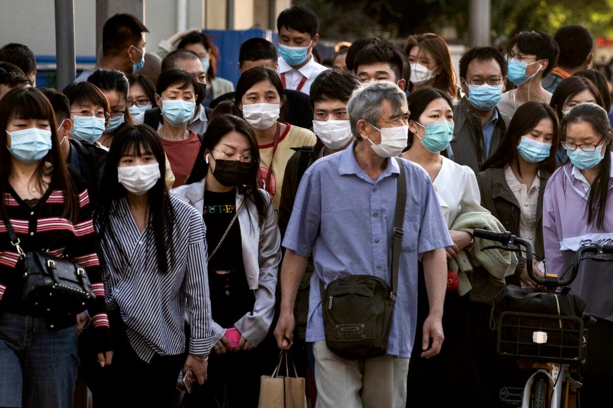 Chinese commuters wear protective masks as they wait to cross an intersection at the end of the workday during rush hour in Beijing, China, on May 18, 2020. (Kevin Frayer/Getty Images)
