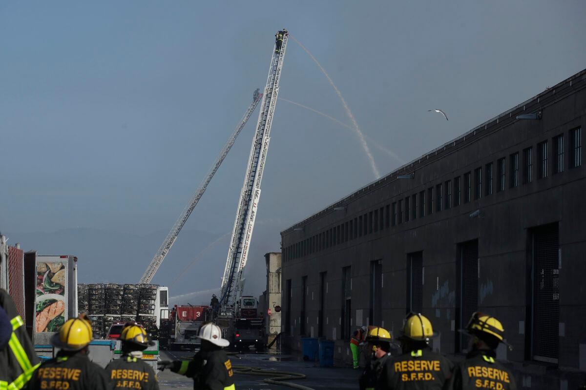 A firefighter sprays into a warehouse after a fire broke out before dawn at Fisherman's Wharf in San Francisco, Saturday, May 23, 2020. (Jeff Chiu/AP photo)
