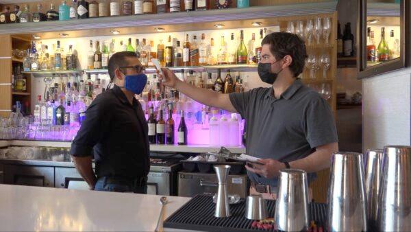 Chef Jason Naaman (R) takes the bartender's temperature before work starts at Tarla Mediterranean Bar and Grill in Napa, Calif., on May 23, 2020. (Ilene Eng/The Epoch Times).