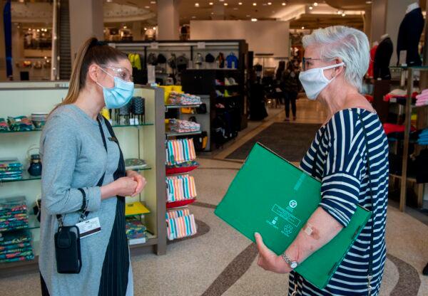 An employee (L) at the Simons store explains health safety procedures to a customer, both wearing facemasks, on Sainte-Catherine Street, in Montreal, Canada, on May 25, 2020. (Photo by Sebastien St-Jean/AFP via Getty Images)